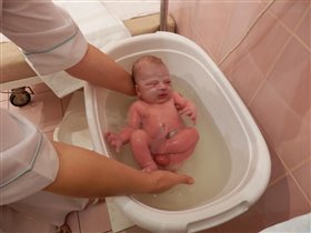 акушерка купает новорожденного Лёву в родзале