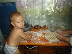 Сын помогает бабуле раскатывать тесто на пельмени